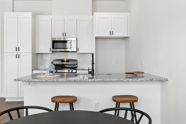 a kitchen with stainless steel appliances granite countertop a stove a sink and white cabinets
