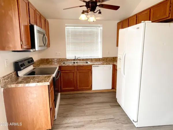a kitchen with stainless steel appliances granite countertop a sink a stove a refrigerator a washer dryer and white cabinets with wooden floor