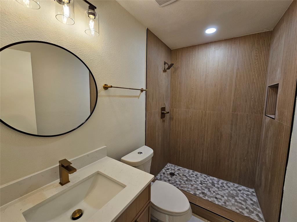 1725 R Avenue, Unit 1727 Plano, TX 75074 - Photo 14 of 20 Bathroom featuring a walk-in shower with floor-to-ceiling wood-finish tile, pebble-style shower pan, and a recessed shower niche