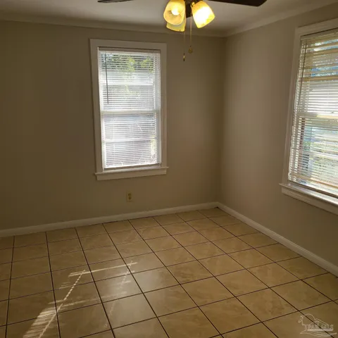 an empty room with windows and chandelier fan