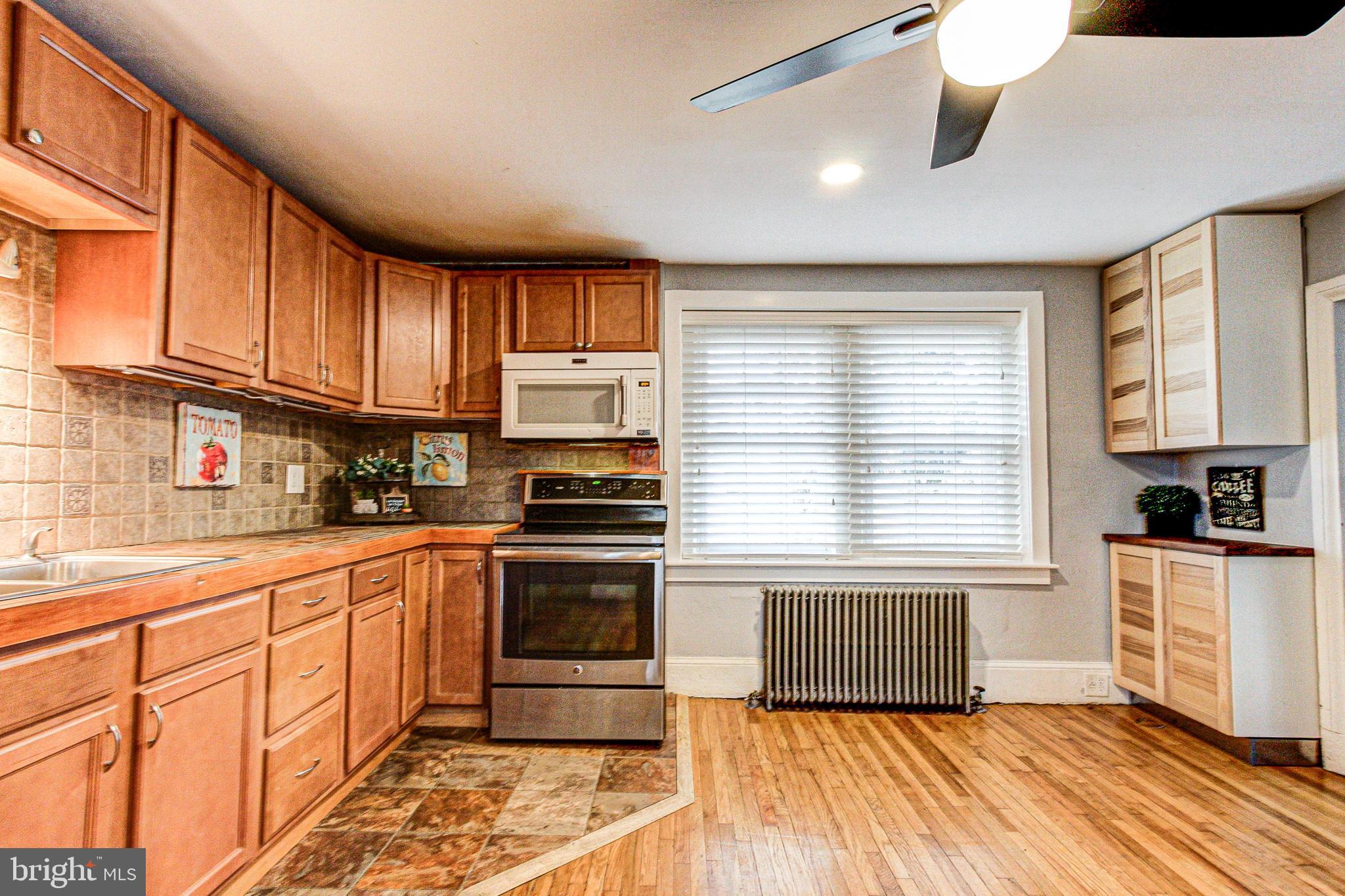 1079 Old Skippack Road Harleysville, PA 19438 - Photo 18 of 53 a kitchen with stainless steel appliances granite countertop a stove a sink and white cabinets with wooden floor