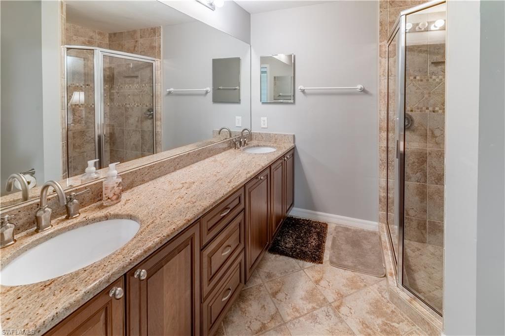 8065 Tiger Cove, Unit 1604 Naples, FL 34113 - Photo 15 of 23 a bathroom with a granite countertop sink a mirror and a shower