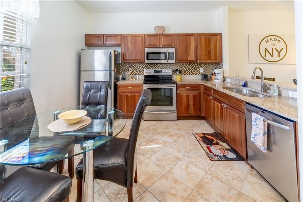 8065 Tiger Cove, Unit 1604 Naples, FL 34113 - Photo 4 of 23 a kitchen with stainless steel appliances granite countertop a sink a stove a refrigerator cabinets and dining table