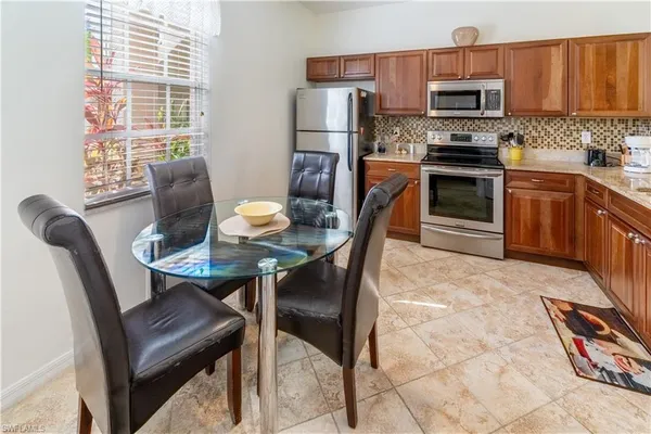 a kitchen with stainless steel appliances a dining table chairs and a refrigerator