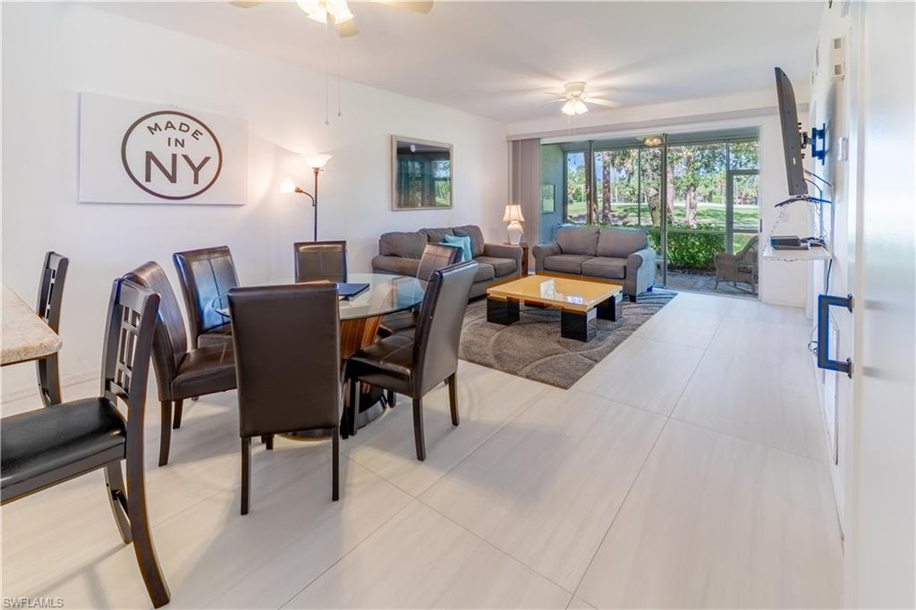 8065 Tiger Cove, Unit 1604 Naples, FL 34113 - Photo 8 of 23 a living room with furniture a clock tv and a window