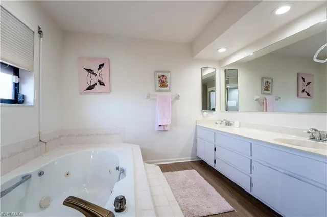 a bathroom with a tub a sink and mirror