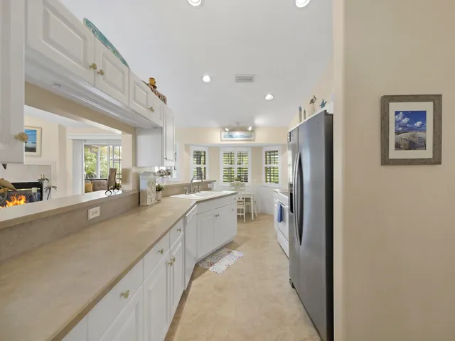 a large white kitchen with a lot of counter space and a refrigerator