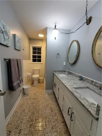 a bathroom with a granite countertop toilet sink and mirror