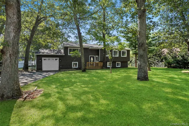 a view of a house with a yard and a large tree
