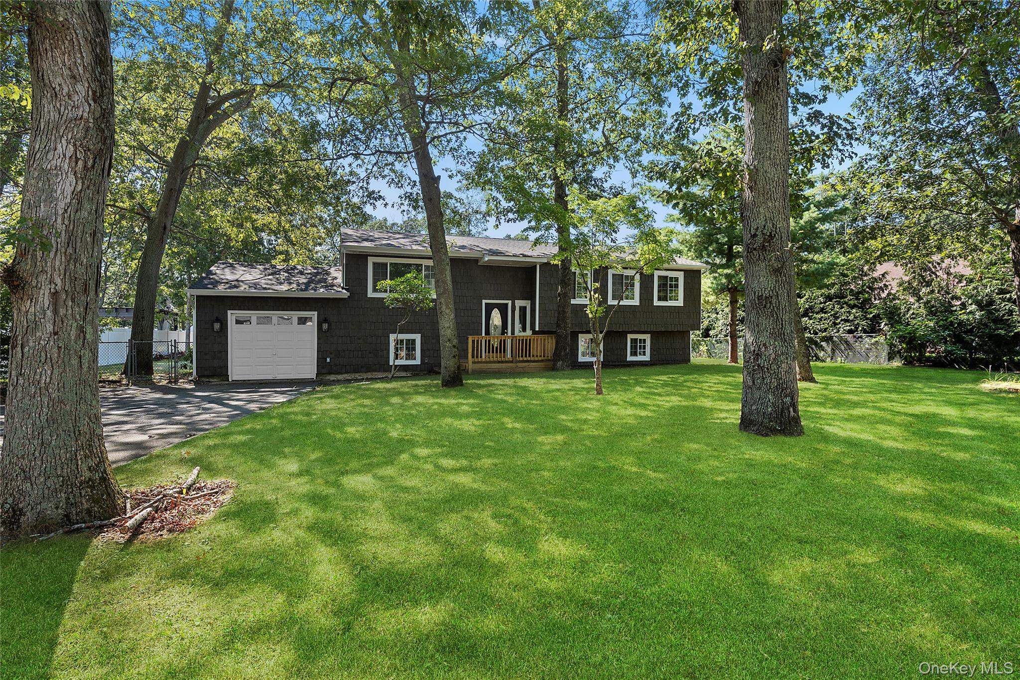 a view of a house with a yard and a large tree