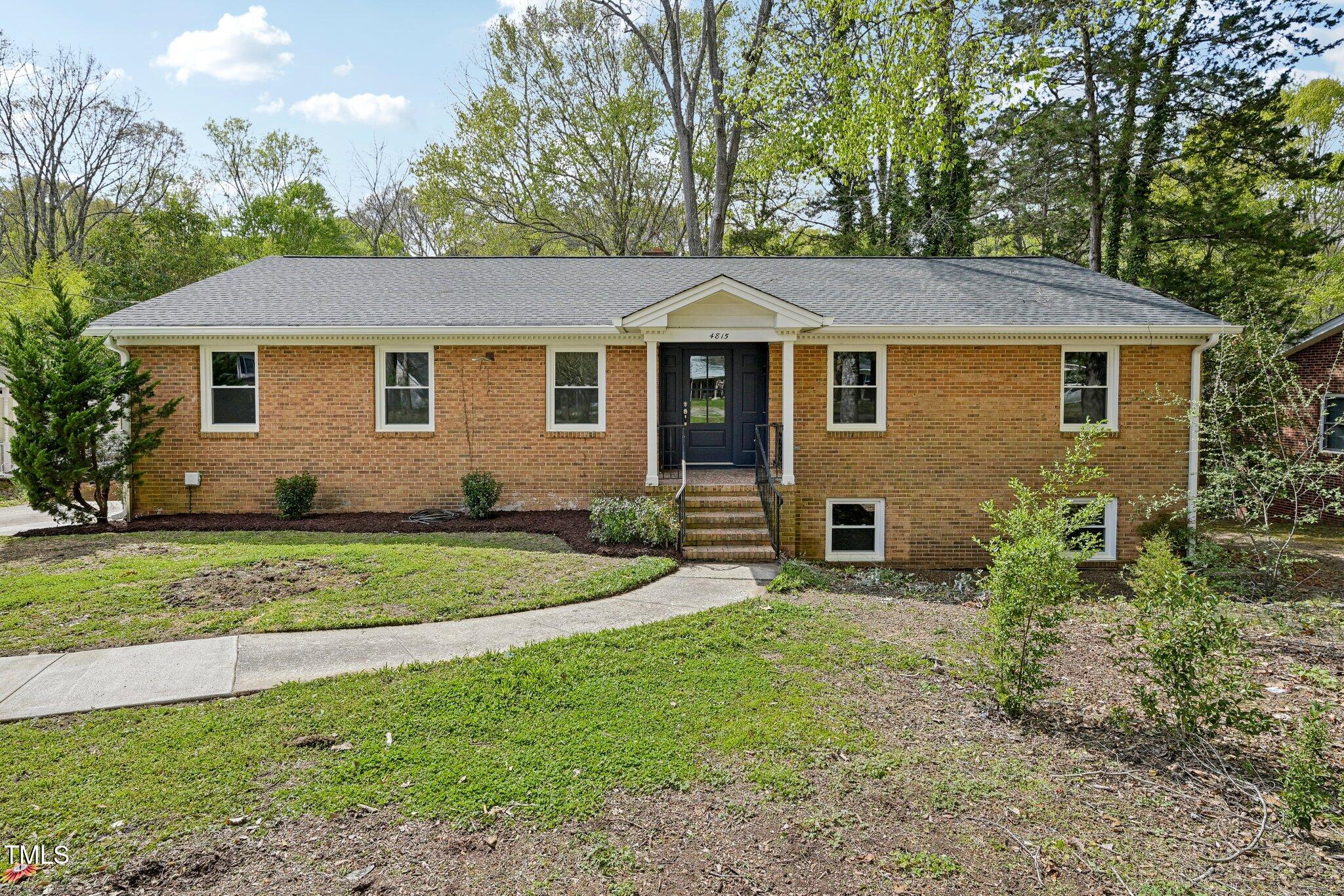 a view of a yard in front of a house with large windows