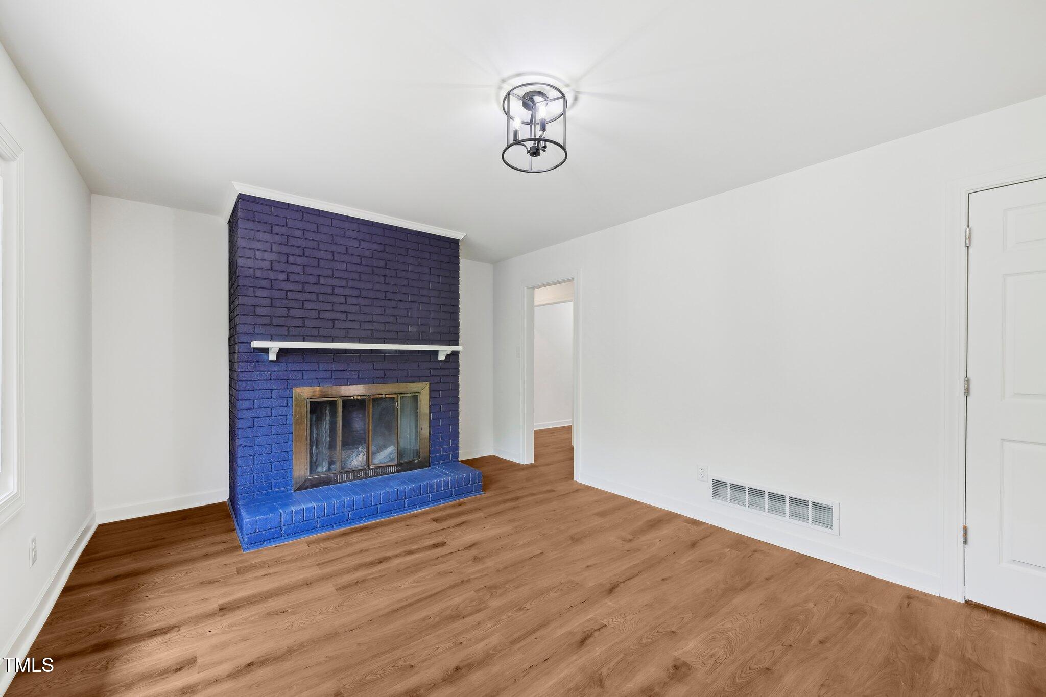 4815 Oak Park Road Raleigh, NC 27612 - Photo 15 of 50 a view of an empty room with wooden floor and a fireplace