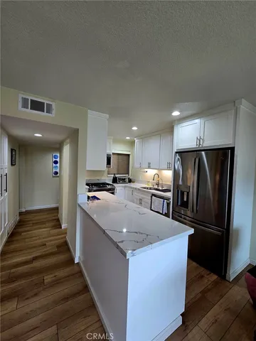 a kitchen with stainless steel appliances granite countertop a refrigerator a stove and a sink