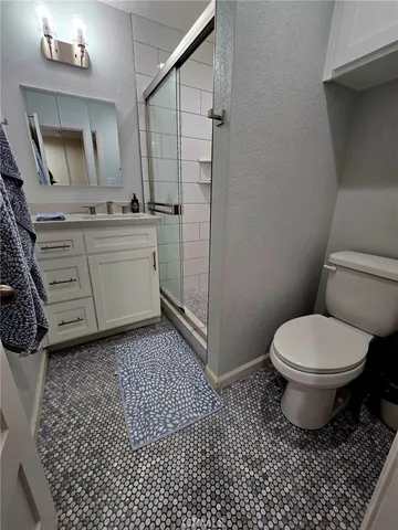 a bathroom with a granite countertop toilet a sink a mirror and vanity