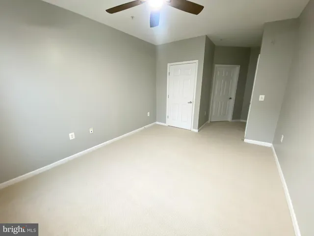 an empty room with a ceiling fan and window