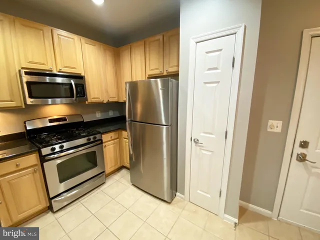 a kitchen with granite countertop a refrigerator and a stove top oven