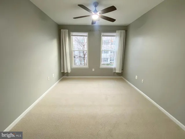 an empty room with windows and ceiling fan