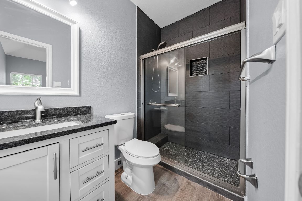 1214 Vargas Road, Unit B Austin, TX 78741 - Photo 15 of 25 a bathroom with a granite countertop sink a toilet and a mirror