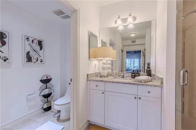 a bathroom with a granite countertop toilet sink and mirror