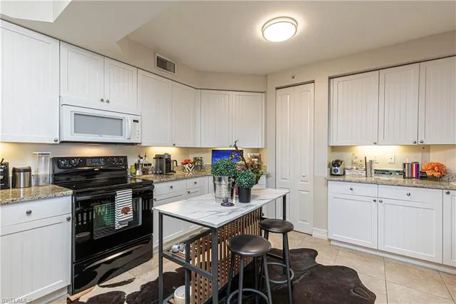 a kitchen with granite countertop a stove top oven a sink dishwasher and white cabinets with wooden floor