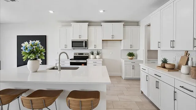 a kitchen with granite countertop a sink white cabinets and stainless steel appliances