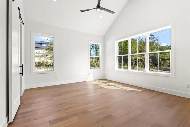 a view of an empty room with a window and wooden floor