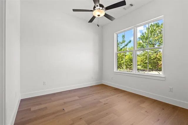 an empty room with wooden floor fan and a window