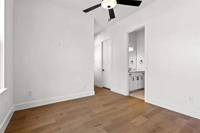 an empty room with wooden floor and ceiling fan