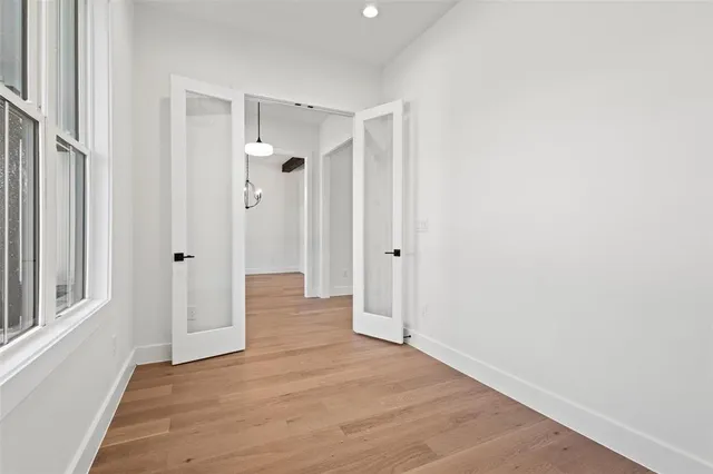 a view of a hallway with wooden floor and a bathroom