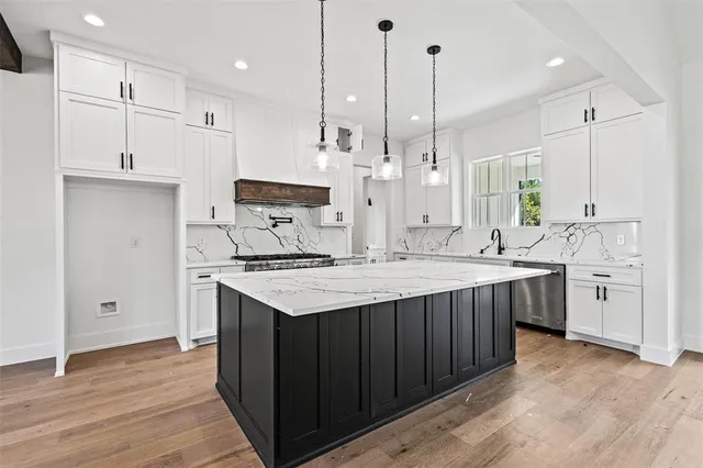 a kitchen with kitchen island a sink stainless steel appliances and wooden floor