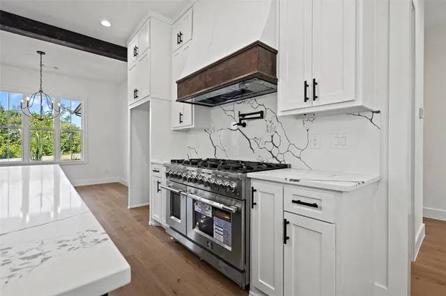 a kitchen with stainless steel appliances granite countertop a stove and a white cabinets