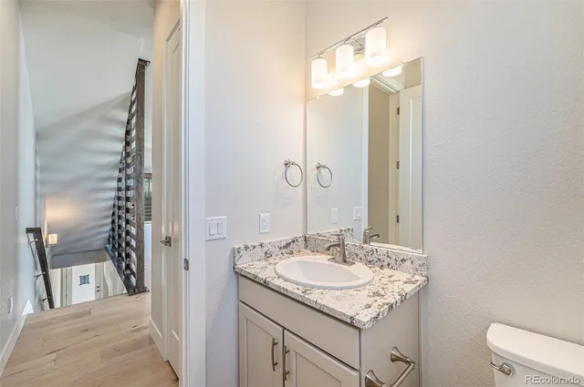 a bathroom with a granite countertop sink a toilet and shower