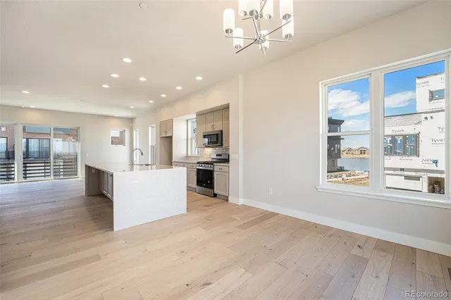an empty room with wooden floor fireplace and windows
