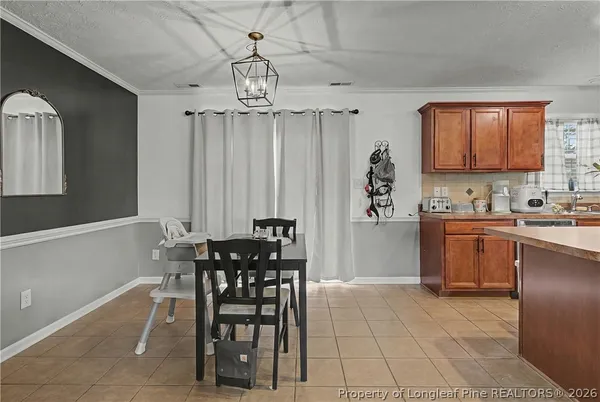 a kitchen with granite countertop a table chairs a sink dishwasher refrigerator and cabinets