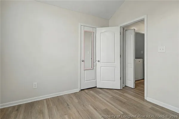 a view of an empty room with wooden floor and closet