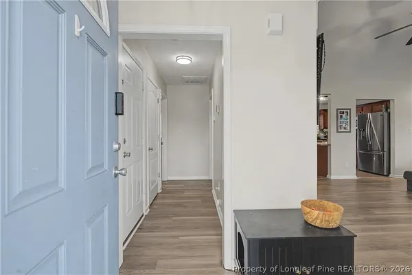 a view of a hallway with wooden floor and a bathroom