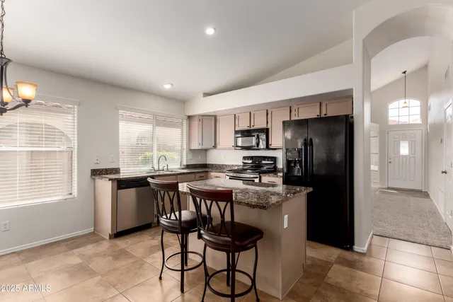 a kitchen with stainless steel appliances granite countertop a refrigerator a stove a sink a dining table and chairs