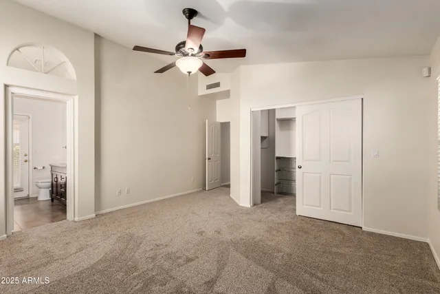 an empty room with closet and a chandelier fan
