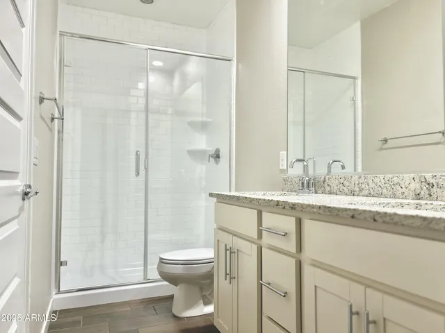 a bathroom with a granite countertop sink a toilet and shower