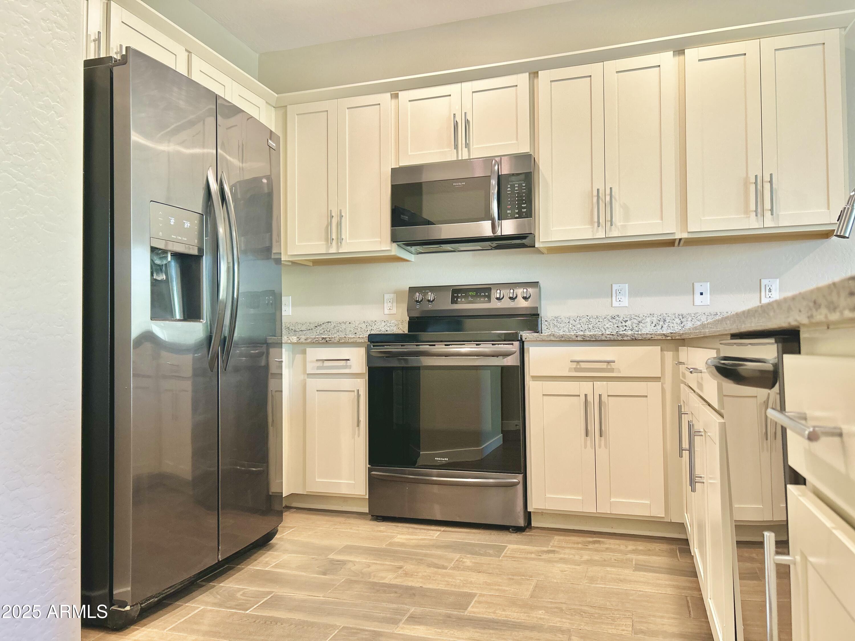 4038 East Erie Street, Unit 103 Gilbert, AZ 85295 - Photo 9 of 16 a kitchen with stainless steel appliances granite countertop a refrigerator and a stove top oven