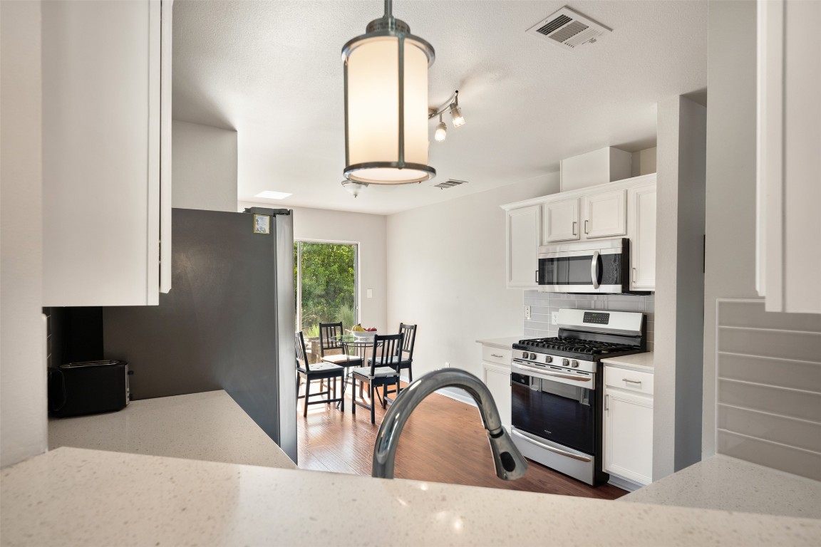 2004 Yaupon Trail Cedar Park, TX 78613 - Photo 12 of 33 a kitchen with stainless steel appliances granite countertop a stove a sink a refrigerator and white cabinets with wooden floor
