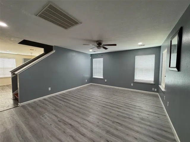 a view of an empty room with window and wooden floor