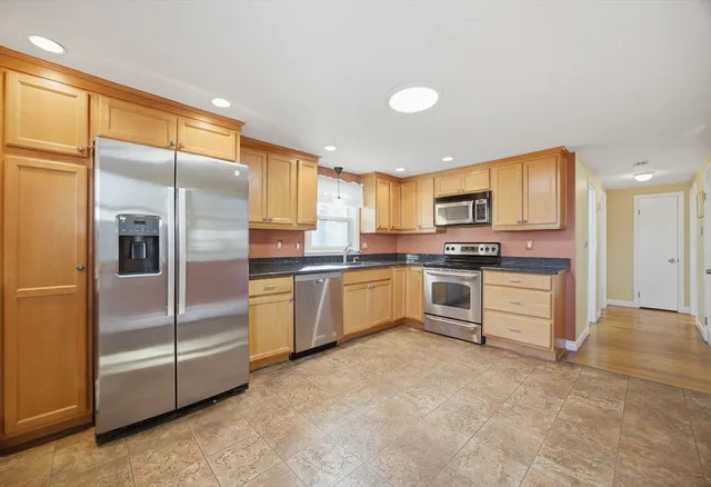 a kitchen with granite countertop a refrigerator and white cabinets