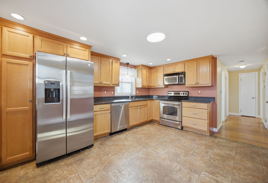 55 Maynard Road Dedham, MA 02026 - Photo 7 of 38 a kitchen with granite countertop a refrigerator and white cabinets