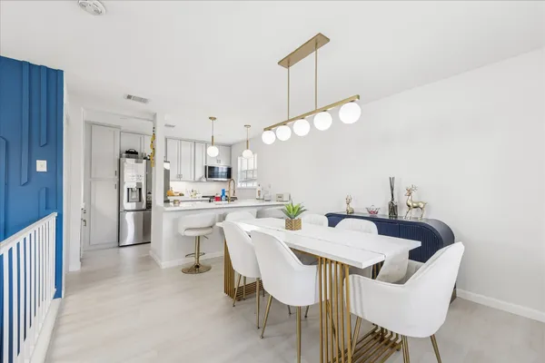 a kitchen with a dining table chairs and refrigerator
