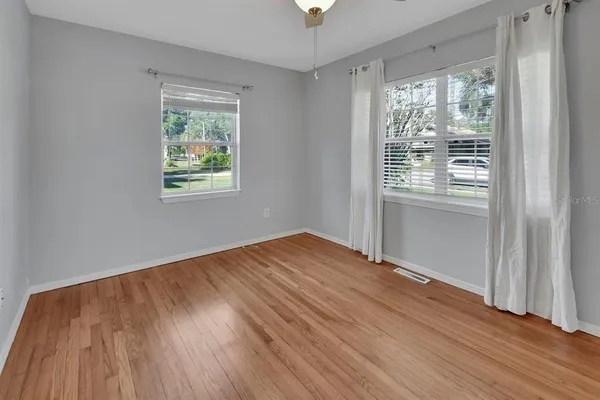 a view of an empty room with wooden floor and a window