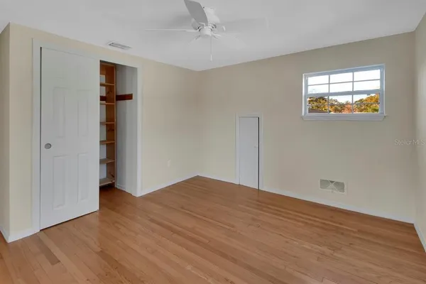 an empty room with wooden floor closet and windows
