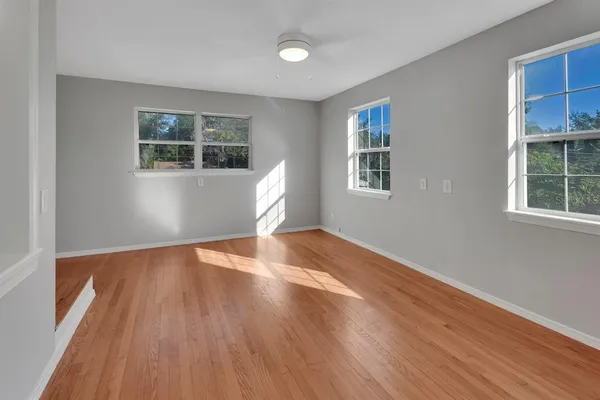 an empty room with wooden floor and windows