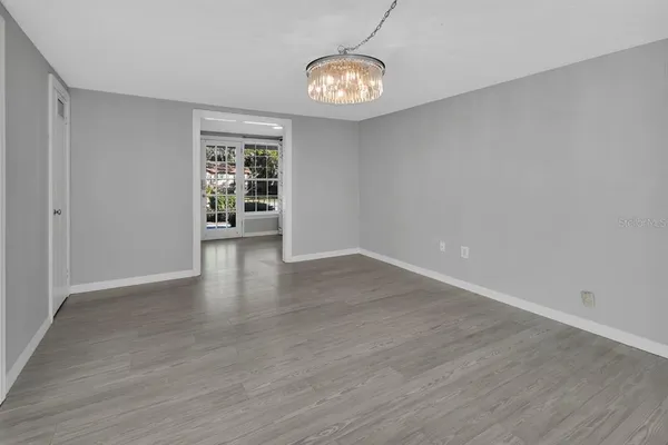 a view of an empty room with wooden floor and window