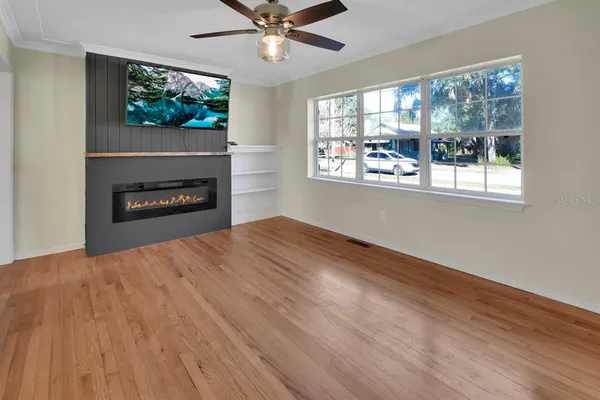 a view of empty room with wooden floor and fan